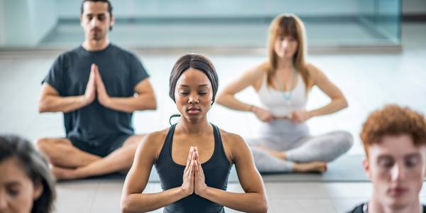 Vrouwen en mannen in een rustgevende yogahouding op een turnmatje